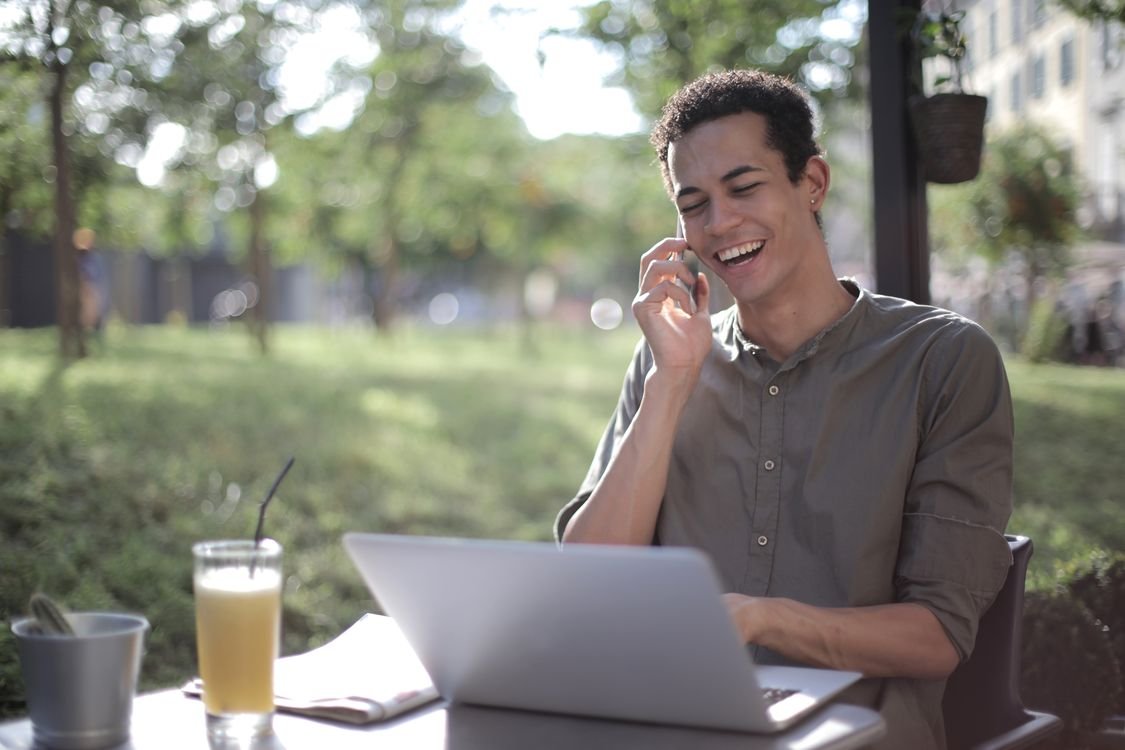 Emprendedor sonriente hablando por teléfono mientras atiende a un cliente