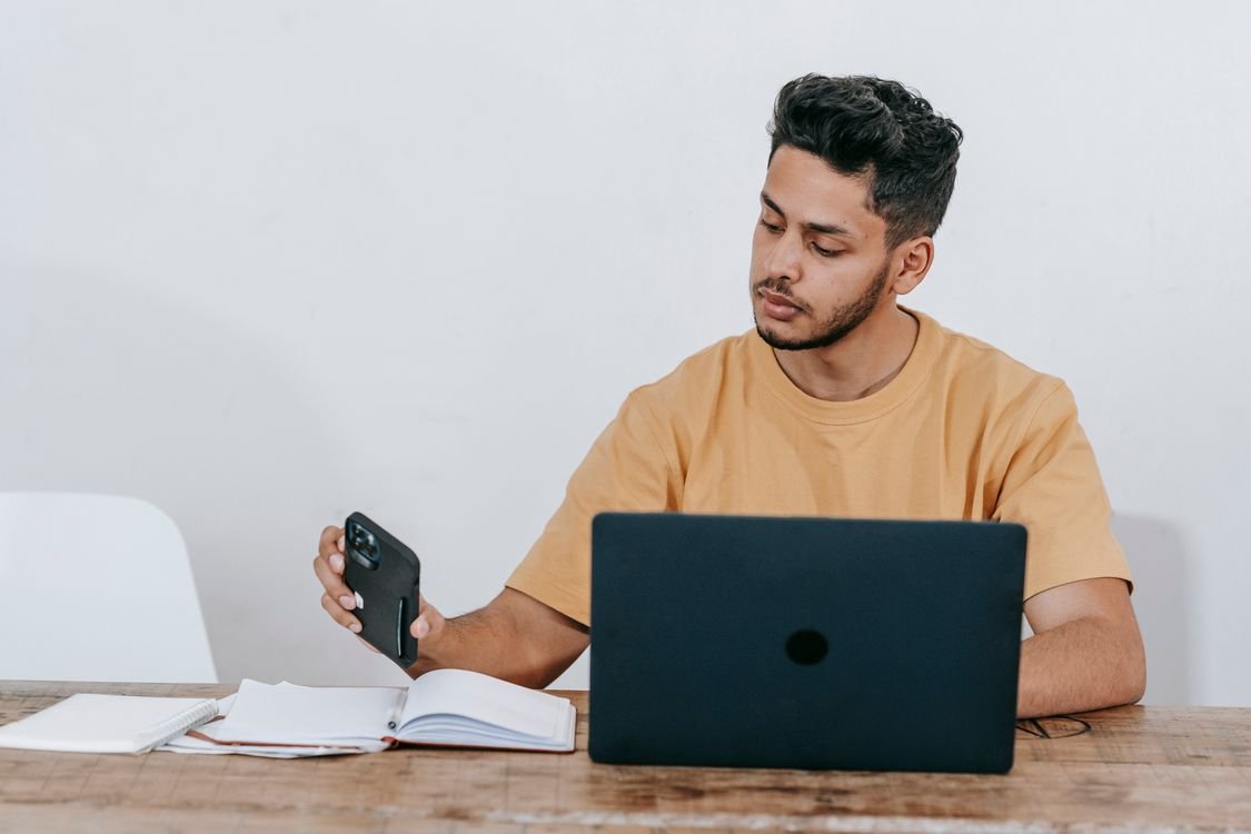 Emprendedor latino trabajando con laptop y teléfono para atender a sus clientes