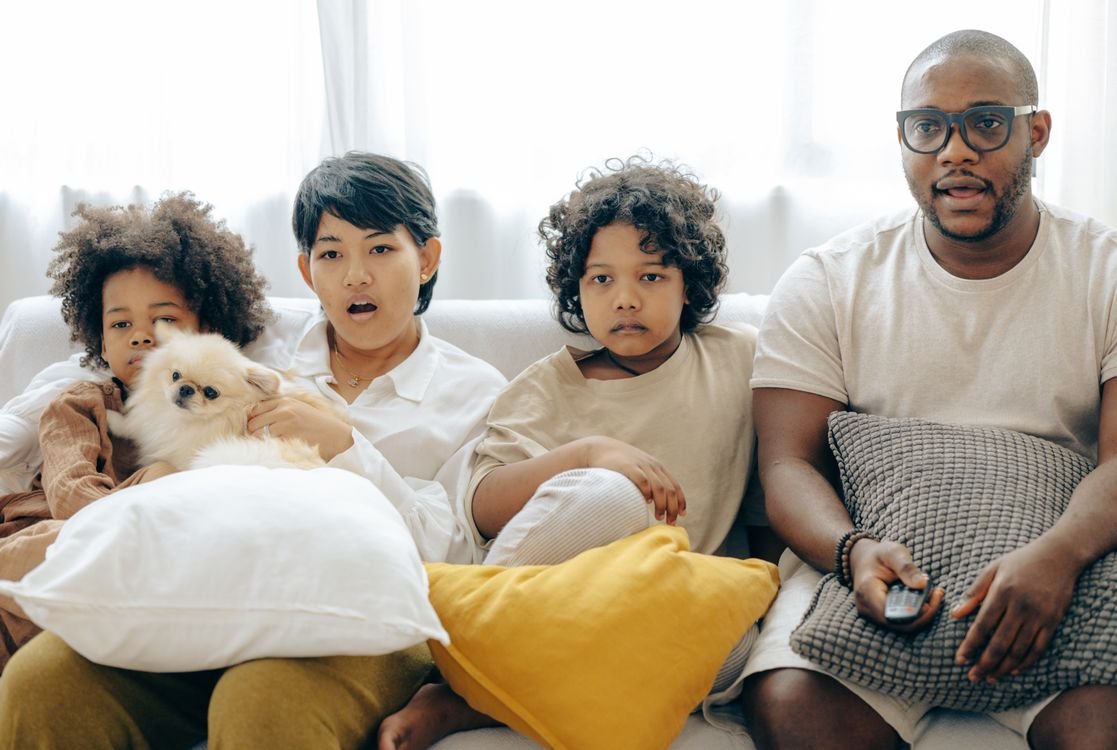 Familia viendo televisión juntos en el sofá de su sala de estar